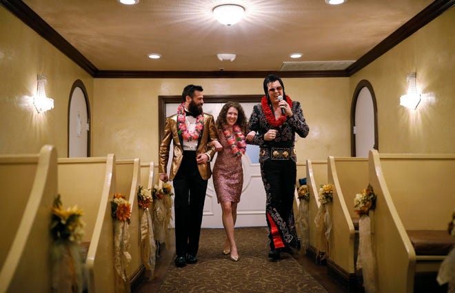 Elvis impersonator Brendan Paul walks down the aisle during a wedding ceremony for Katie Salvatore, center, and Eric Wheeler at the Graceland Wedding Chapel in Las Vegas.