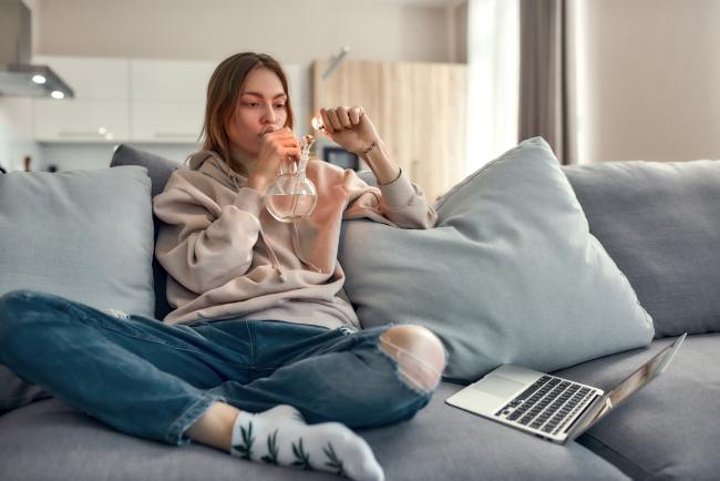 a woman relaxing on the couch smoking a bong